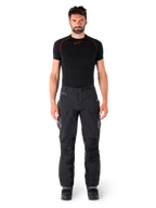 Pantaloni Alpinestars Hyde XT Drystar®, pantaloni da moto adventure touring, nero, indossati da un modello con base layer nero a maniche corte e stivali neri, caratterizzati da materiale tecnico elasticizzato, pannelli rinforzati sulle ginocchia e tasche cargo ergonomiche