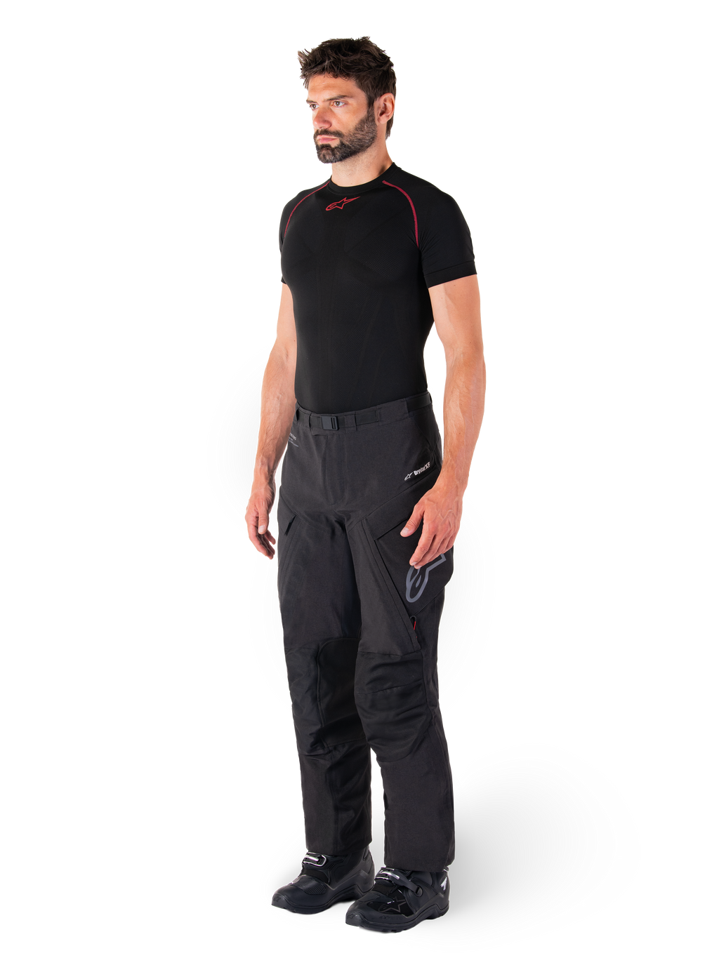 Alpinestars Hyde XT Drystar® Pants, pantaloni da moto adventure touring neri indossati da un modello con maglia a compressione nera e stivali neri, con costruzione tecnica impermeabile e marchio Drystar®XF.