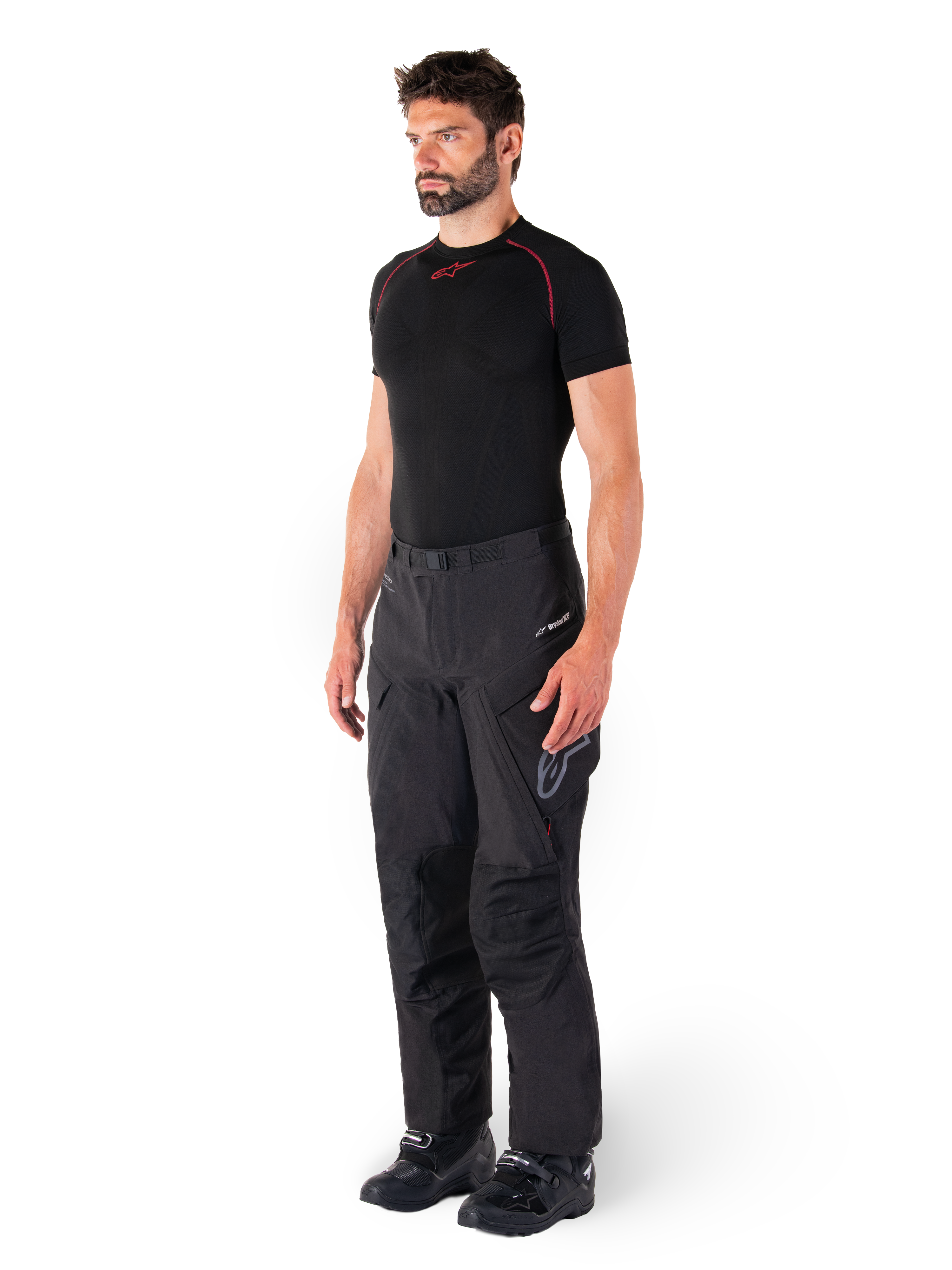 Alpinestars Hyde XT Drystar® Pants, pantaloni da moto adventure touring neri indossati da un modello con maglia a compressione nera e stivali neri, con costruzione tecnica impermeabile e marchio Drystar®XF.