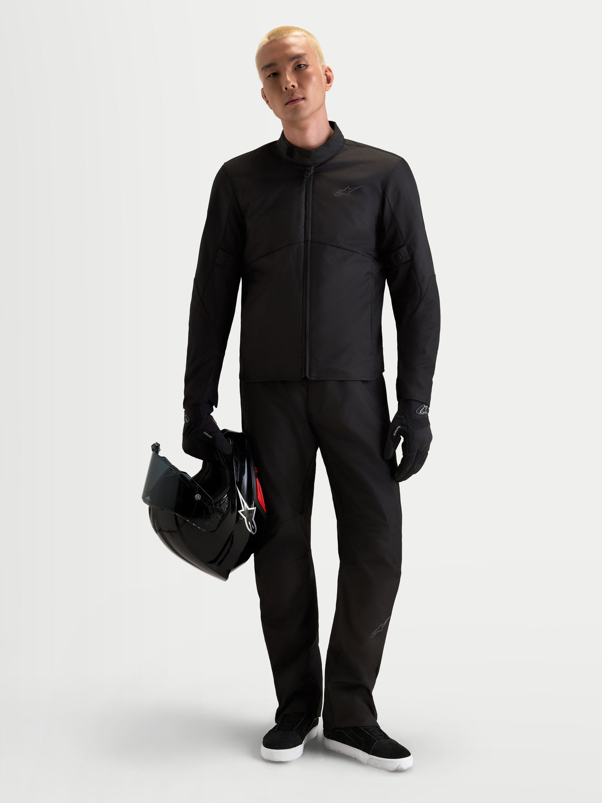 Alpinestars C 1 Waterproof Pantaloni, pantaloni da moto urban da uomo in nero, taglio dritto con protezione certificata CE, indossati da un modello che tiene in mano un casco
