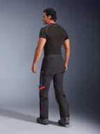 Alpinestars Halo Pro Drystar® XF Pantaloni Laminati, Nero Dark Shadow con accenti rossi, vista posteriore su modello, abbinati a base layer nero e stivali da moto, abbigliamento tecnico da adventure touring per ogni terreno