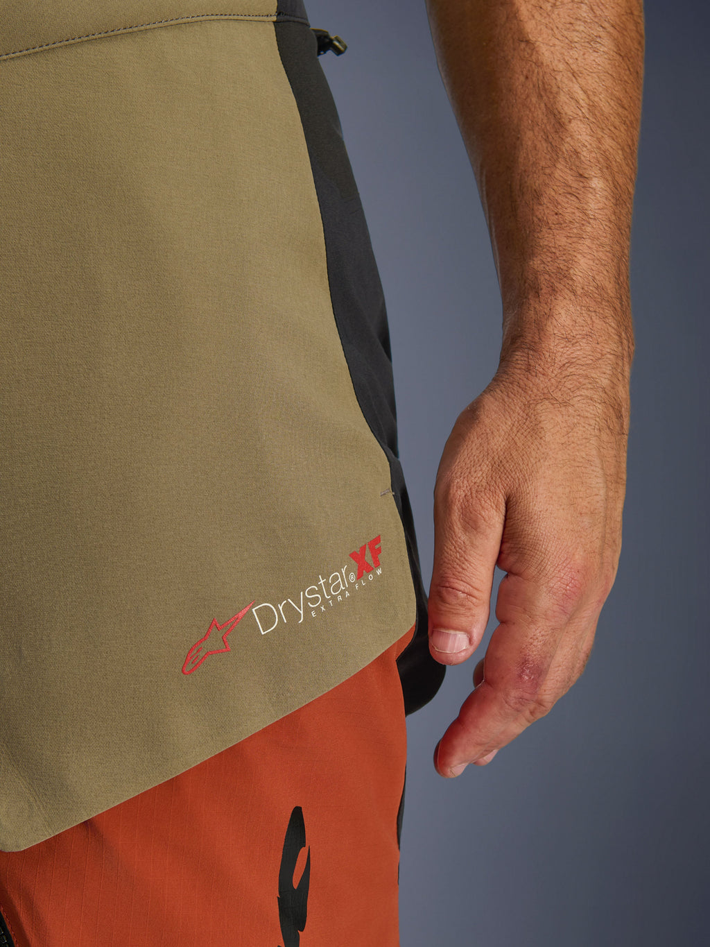 Alpinestars Halo Pro Drystar® XF Laminated Pants, Walnut Rust Black, dettaglio ravvicinato del marchio Drystar XF Extra Flow, pannelli in tessuto verde oliva e arancione ruggine, costruzione tecnica