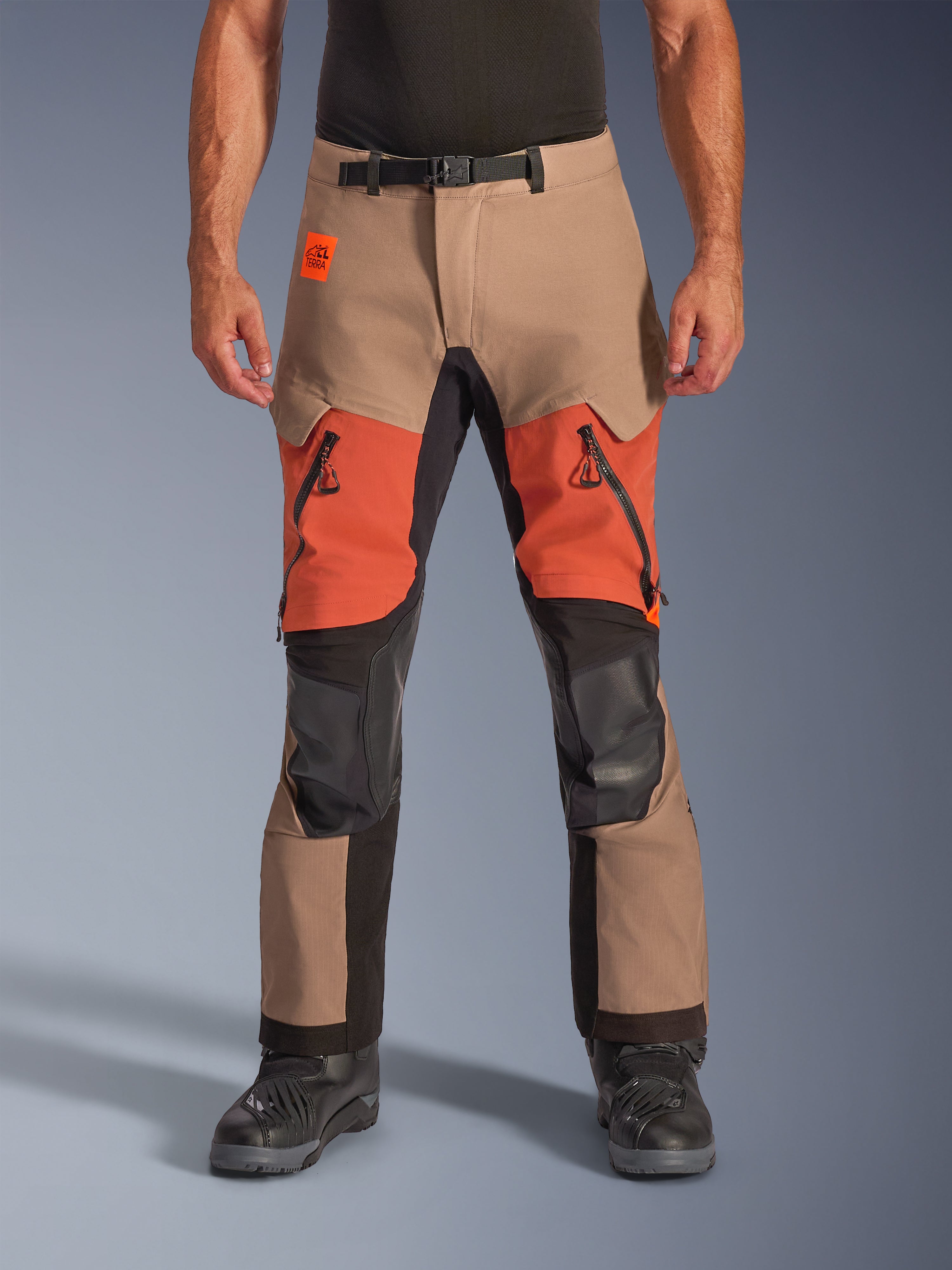 Pantaloni Alpinestars Halo Pro Drystar XF Laminated, pantaloni da moto adventure touring, noce, ruggine e nero, con costruzione laminata impermeabile, vista frontale con prese d'aria arancioni sulle cosce, cerniere YKK AQUASEAL nere e cintura regolabile in vita.