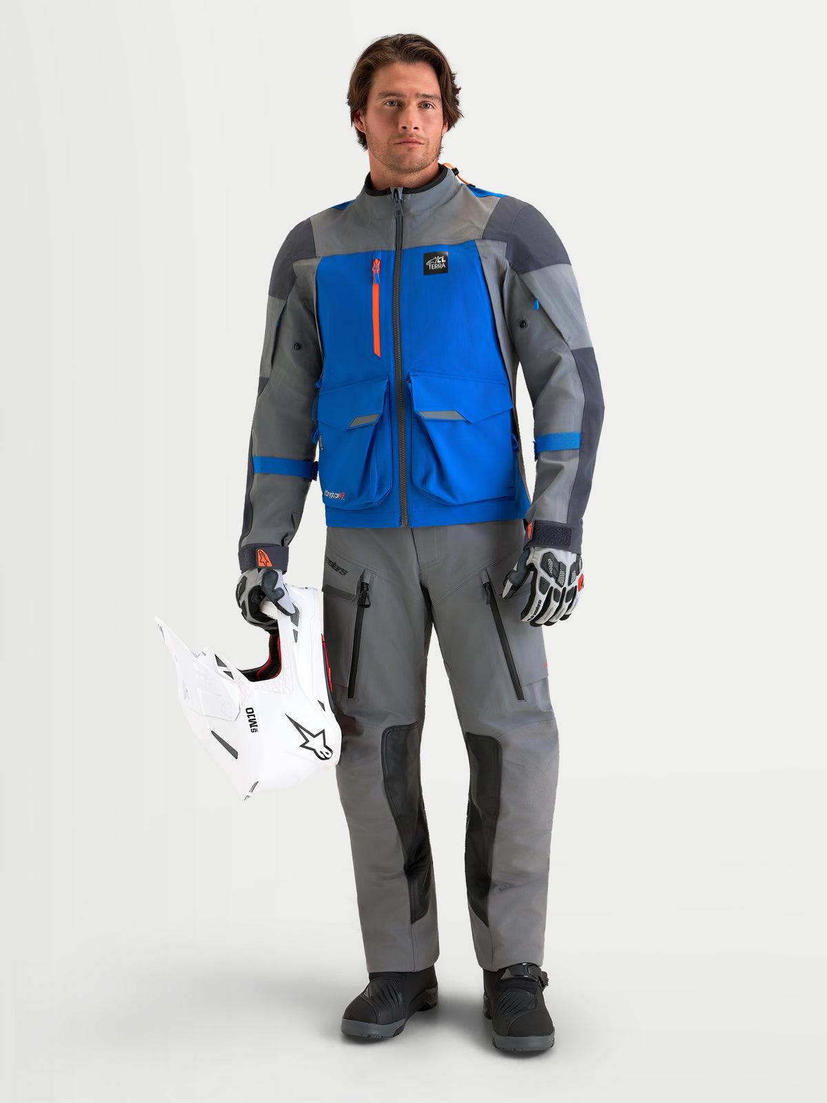 Alpinestars Maxdura Drystar XF Laminated Pantaloni, pantaloni da moto adventure da uomo in grigio scuro e nero, indossati da un modello che tiene un casco da off-road bianco