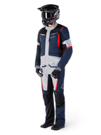 Pantaloni Alpinestars St-1 Waterproof, pantaloni da adventure touring, blu scuro, nero e rosso acceso, indossati con giacca da touring coordinata, casco nero, guanti e stivali, con pannelli grigio chiaro, accenti rossi e marchio Alpinestars, progettati per la guida in ogni condizione atmosferica
