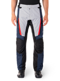 Alpinestars ST-1 Waterproof Pants, pantaloni da moto touring, blu scuro e grigio chiaro con dettagli rosso acceso, pannelli neri rinforzati sulle ginocchia, vista frontale con stivali neri, abbigliamento impermeabile per adventure touring