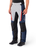 Pantaloni Alpinestars St-1 Waterproof, pantaloni da touring per moto, blu scuro, nero e rosso brillante, caratterizzati da pannelli anteriori grigio chiaro con dettagli delle cerniere rossi, sezioni delle ginocchia rinforzate nere e logo Alpinestars bianco sul lato, indossati con stivali da moto neri.