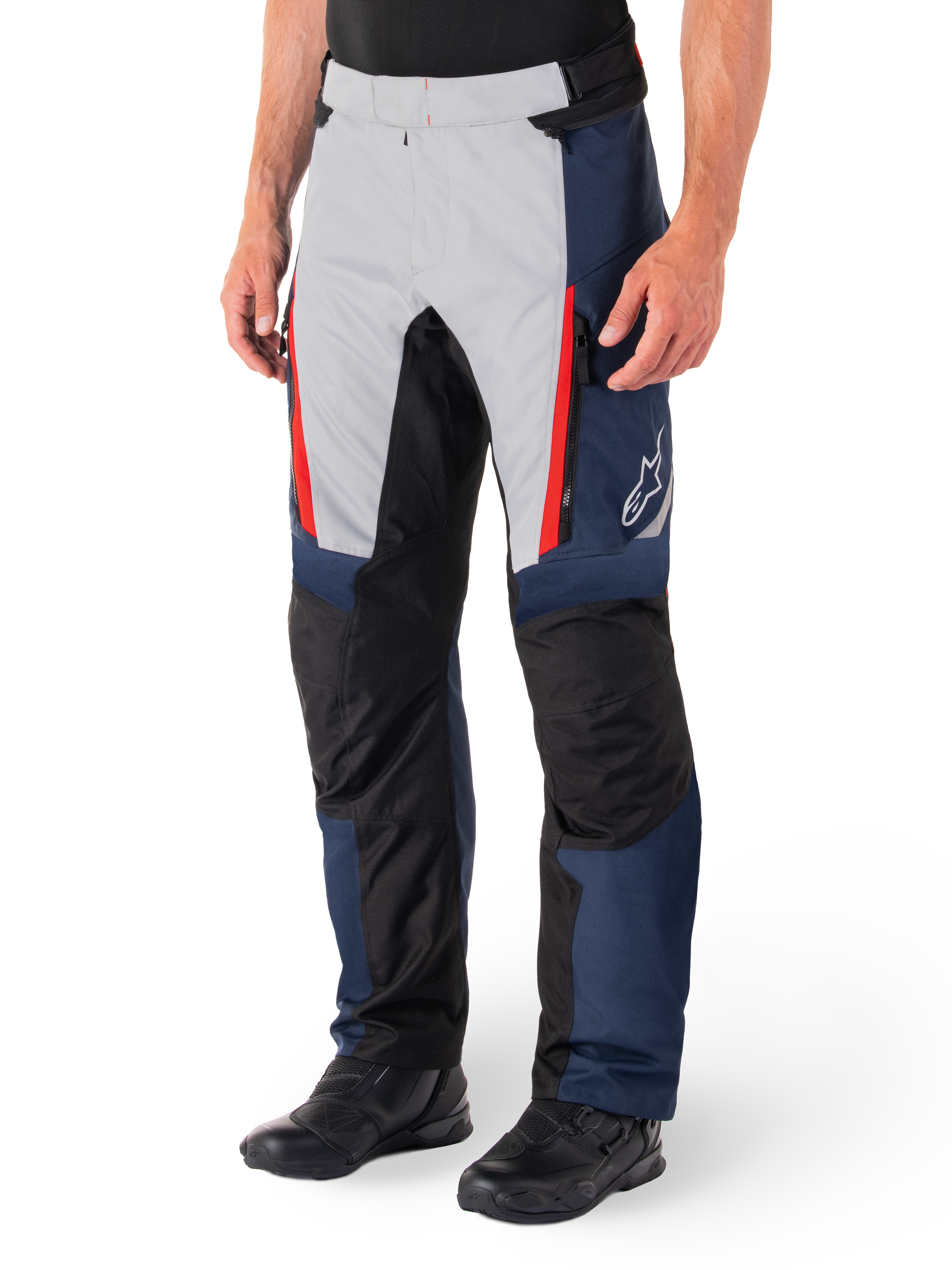 Pantaloni Alpinestars St-1 Waterproof, pantaloni da touring per moto, blu scuro, nero e rosso brillante, caratterizzati da pannelli anteriori grigio chiaro con dettagli delle cerniere rossi, sezioni delle ginocchia rinforzate nere e logo Alpinestars bianco sul lato, indossati con stivali da moto neri.