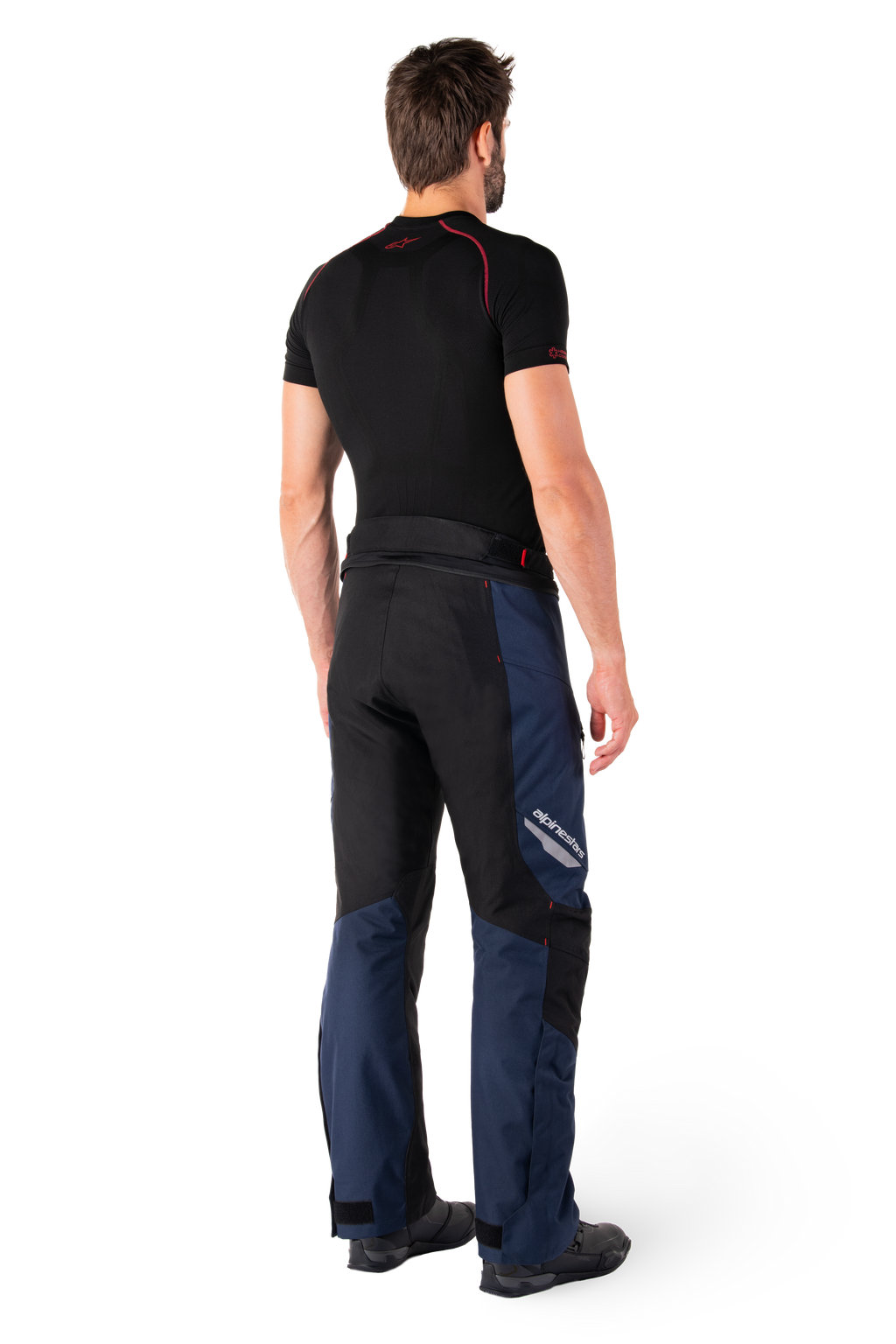 Alpinestars St-1 Waterproof Pants, pantaloni Adventure Touring, blu scuro, nero e rosso acceso, vista laterale posteriore indossati con base layer nero a maniche corte e stivali da moto neri, design aerodinamico con marchio riflettente e dettagli rossi
