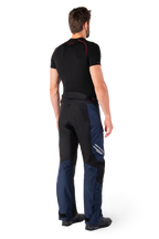 Alpinestars St-1 Waterproof Pants, pantaloni Adventure Touring, blu scuro, nero e rosso acceso, vista laterale posteriore indossati con base layer nero a maniche corte e stivali da moto neri, design aerodinamico con marchio riflettente e dettagli rossi