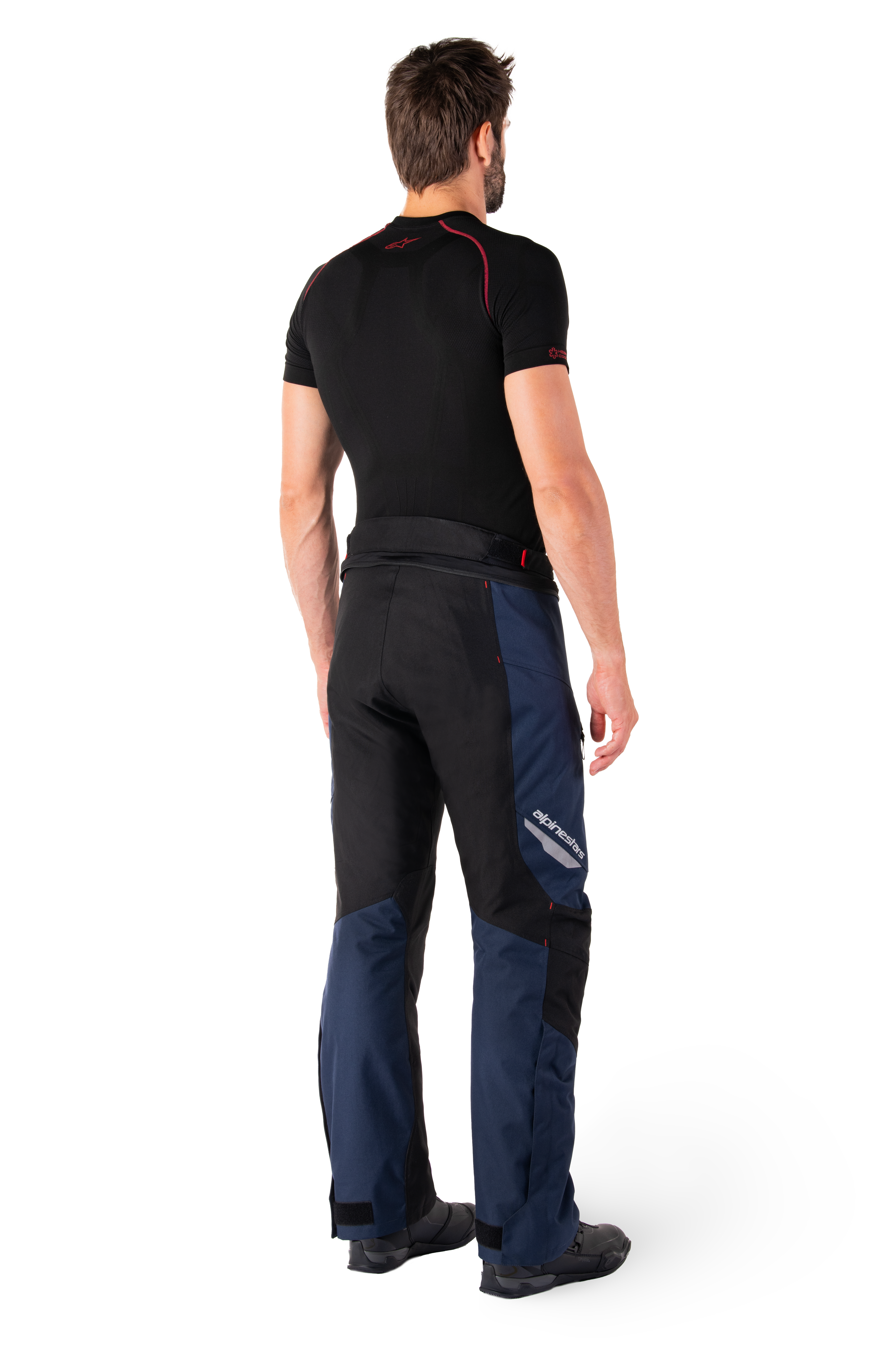 Alpinestars St-1 Waterproof Pants, pantaloni Adventure Touring, blu scuro, nero e rosso acceso, vista laterale posteriore indossati con base layer nero a maniche corte e stivali da moto neri, design aerodinamico con marchio riflettente e dettagli rossi