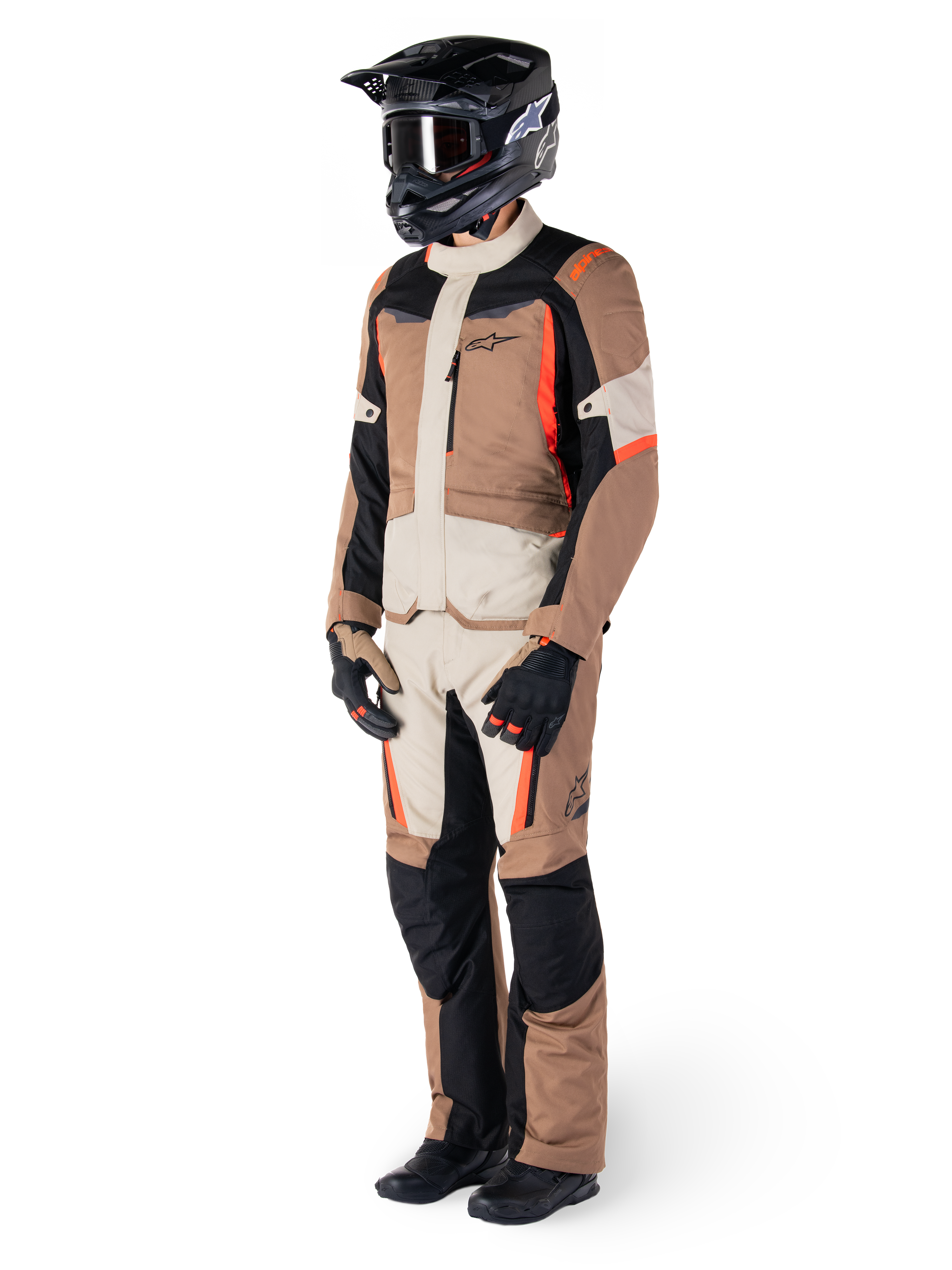 Rider wearing Alpinestars ST-1 Waterproof adventure touring suit, Dark Khaki Sand and Black jacket and pants with Red Fluo accents, black helmet and gloves, showcasing a complete waterproof outfit for all-weather motorcycle riding