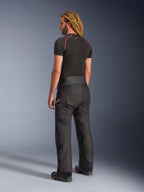 Pantaloni Alpinestars Andes V4 Drystar® - Short, nero, vista posteriore di tre quarti su un modello con lunghi capelli biondi, indossati con una t-shirt base layer nera con cuciture rosse e stivali da moto, design tecnico da adventure touring con pannelli in tessuto resistente.
