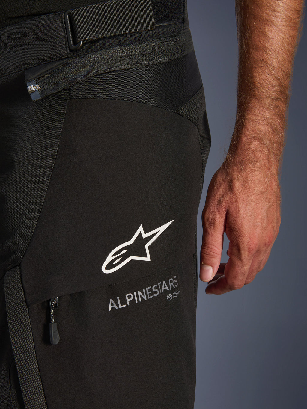 Pantaloni Alpinestars Andes V4 Drystar®, dettaglio ravvicinato di pantaloni da moto neri, con logo Alpinestars bianco e scritta sulla coscia, texture dei tessuti tecnici, zip e cinturino regolabile in vita, abbigliamento adventure touring