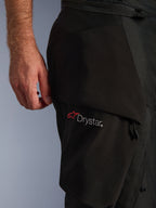 Alpinestars Andes V4 Drystar® Pants, nero, primo piano della zona della coscia con logo Drystar® su una tasca cargo, materiale in tessuto tecnico con pannelli rinforzati, pantaloni da moto adventure impermeabili
