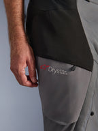 Alpinestars Pantaloni Andes V4 Drystar®, Nero Grigio Scuro, primo piano del dettaglio sulla coscia con logo a stella rosso e marchio Drystar®, robusta struttura in tessuto con tasca con cerniera, abbigliamento per guida adventure