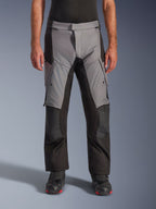 Alpinestars Andes V4 Drystar® Pants, pantaloni da moto adventure touring, grigio e nero, vista frontale indossati da un modello con stivali da guida neri, caratterizzati da rinforzi sulle ginocchia e tasche cargo sulle cosce, costruzione in tessuto impermeabile e traspirante per tutte le condizioni atmosferiche