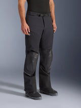 Alpinestars Andes Pro Drystar® XF Pants, pantaloni da moto adventure, nero e grigio scuro, indossati da un modello con stivali da moto neri, con pannelli rinforzati sulle ginocchia, cintura regolabile con fibbia magnetica, tasche con cerniera e costruzione in tessuto laminato resistente per ogni condizione atmosferica