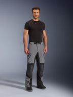 Alpinestars Andes Pro Drystar® XF Pants, pantaloni da moto adventure, grigio scuro e nero, indossati da un modello con un base layer tecnico nero, caratterizzati da una costruzione multi-pannello con cerniere impermeabili e zone rinforzate per il motociclismo d'avventura.