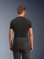 Pantaloni Alpinestars Cusco Drystar®, pantaloni da moto neri, vista posteriore di un pilota che indossa abbigliamento adventure touring con una maglia a compressione nera a maniche corte e cuciture rosse, robusta costruzione in tessuto ripstop e 600D.