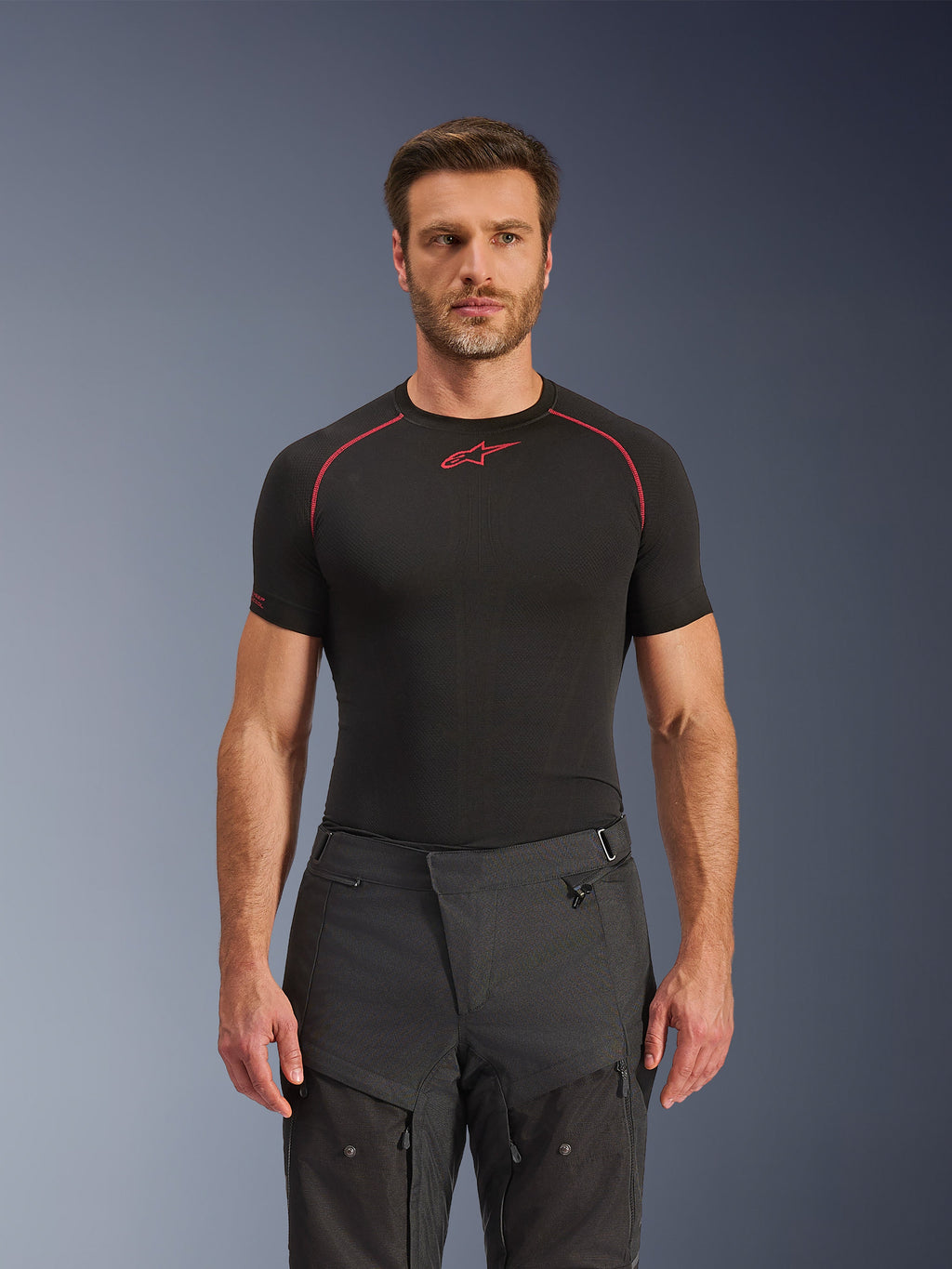 Pantaloni Alpinestars Cusco Drystar®, pantaloni da moto adventure, nero, costruzione in tessuto tecnico con ventilazione a cerniera e pannelli in ripstop, indossati da un modello con maglia base layer Alpinestars nera per un look adventure completo