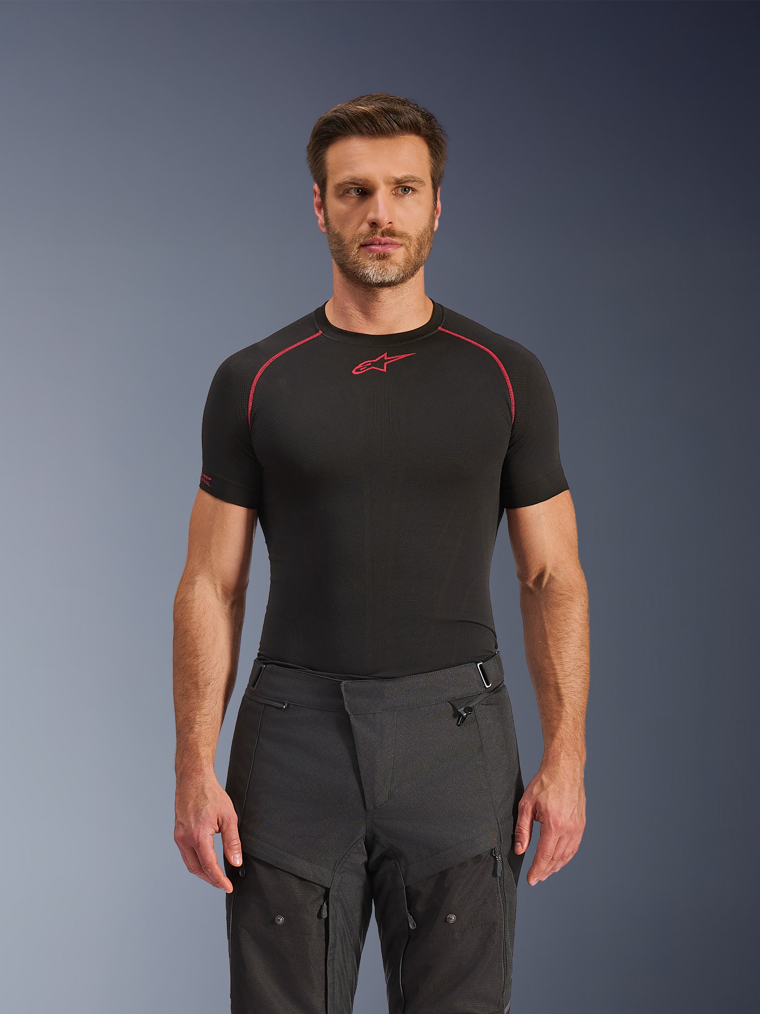 Pantaloni Alpinestars Cusco Drystar®, pantaloni da moto adventure, nero, costruzione in tessuto tecnico con ventilazione a cerniera e pannelli in ripstop, indossati da un modello con maglia base layer Alpinestars nera per un look adventure completo