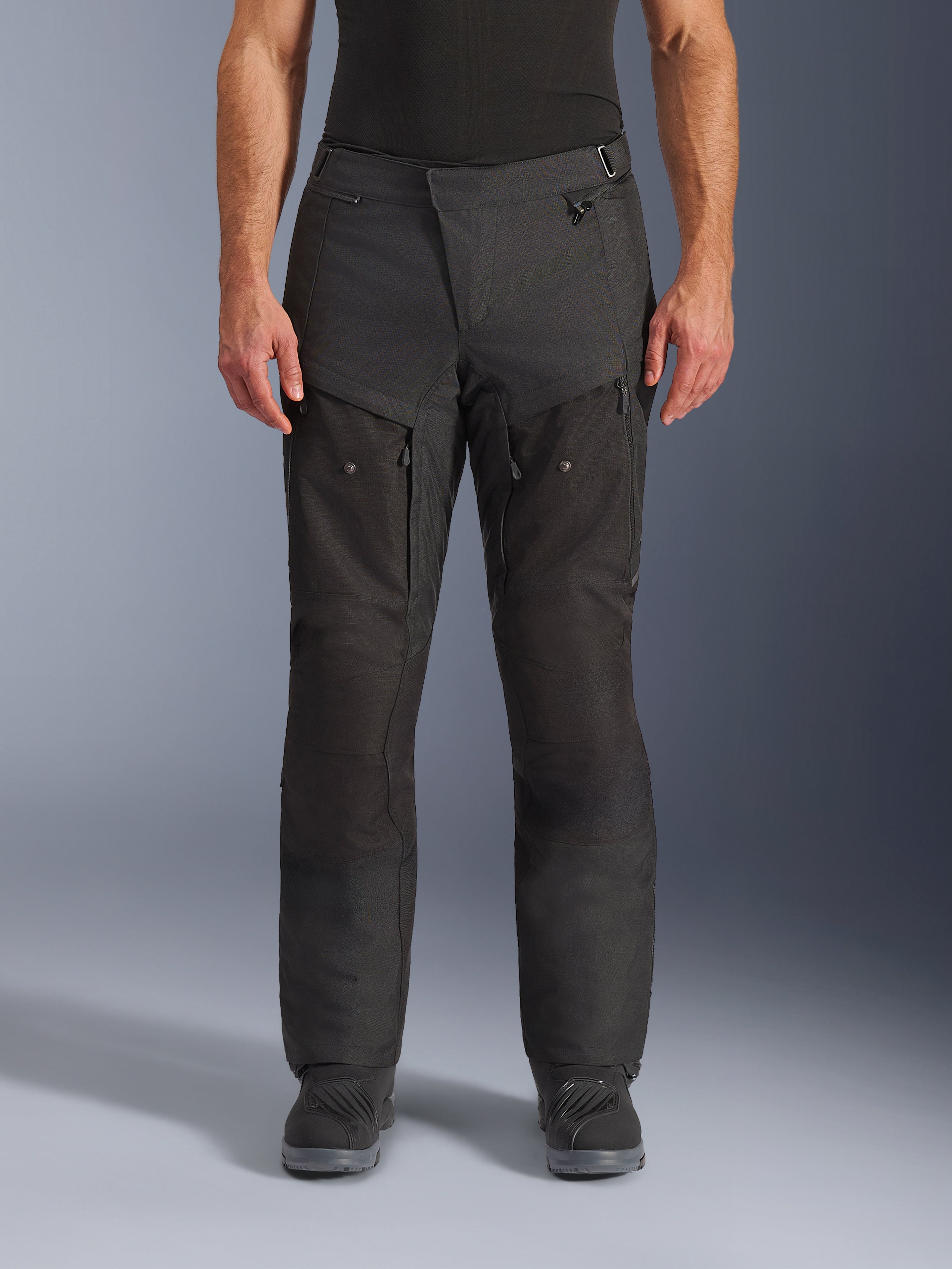 Alpinestars Cusco Drystar® Pants, pantaloni da moto adventure, nero, vista frontale, con ventilazione sulle cosce con cerniera e vita regolabile, costruzione in resistente ripstop e tessuto 600D, indossati con stivali neri
