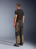 Pantaloni Alpinestars Cusco Drystar®, pantaloni da moto adventure, Walnut Black, vista posteriore a tre quarti indossati con base layer nero e stivali, con pannelli in tessuto rinforzato, tasche cargo con zip sulle cosce e vestibilità touring ergonomica.