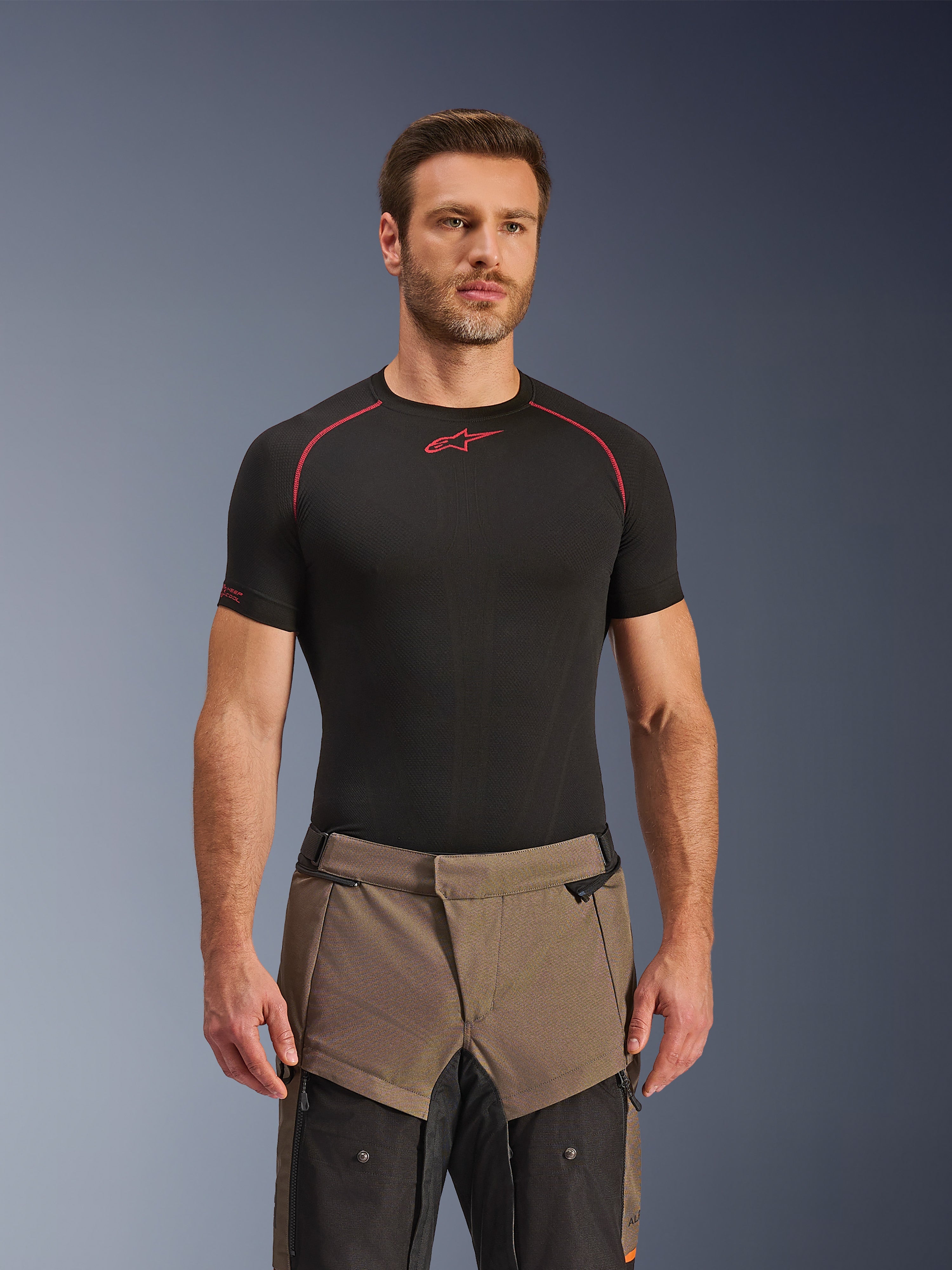 Alpinestars Cusco Drystar® Pants, pantaloni da moto adventure Walnut Black, indossati da un modello con una maglia base layer Alpinestars nera, caratterizzati da un design in tessuto bicolore marrone e nero con pannelli rinforzati per il touring.
