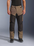 Pantaloni Alpinestars Cusco Drystar®, pantaloni da moto adventure touring, noce e nero con accenti arancioni, vista frontale su modello, caratterizzati da costruzione in tessuto tecnico, tasche cargo e cerniere di ventilazione, indossati con stivali da moto neri