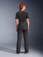 Vista posteriore di una modella che indossa i pantaloni Alpinestars Stella Andes V4 Drystar® neri, abbinati a un base layer nero a maniche corte con logo Alpinestars rosso, abbigliamento da moto adventure-touring con struttura in tessuto resistente.