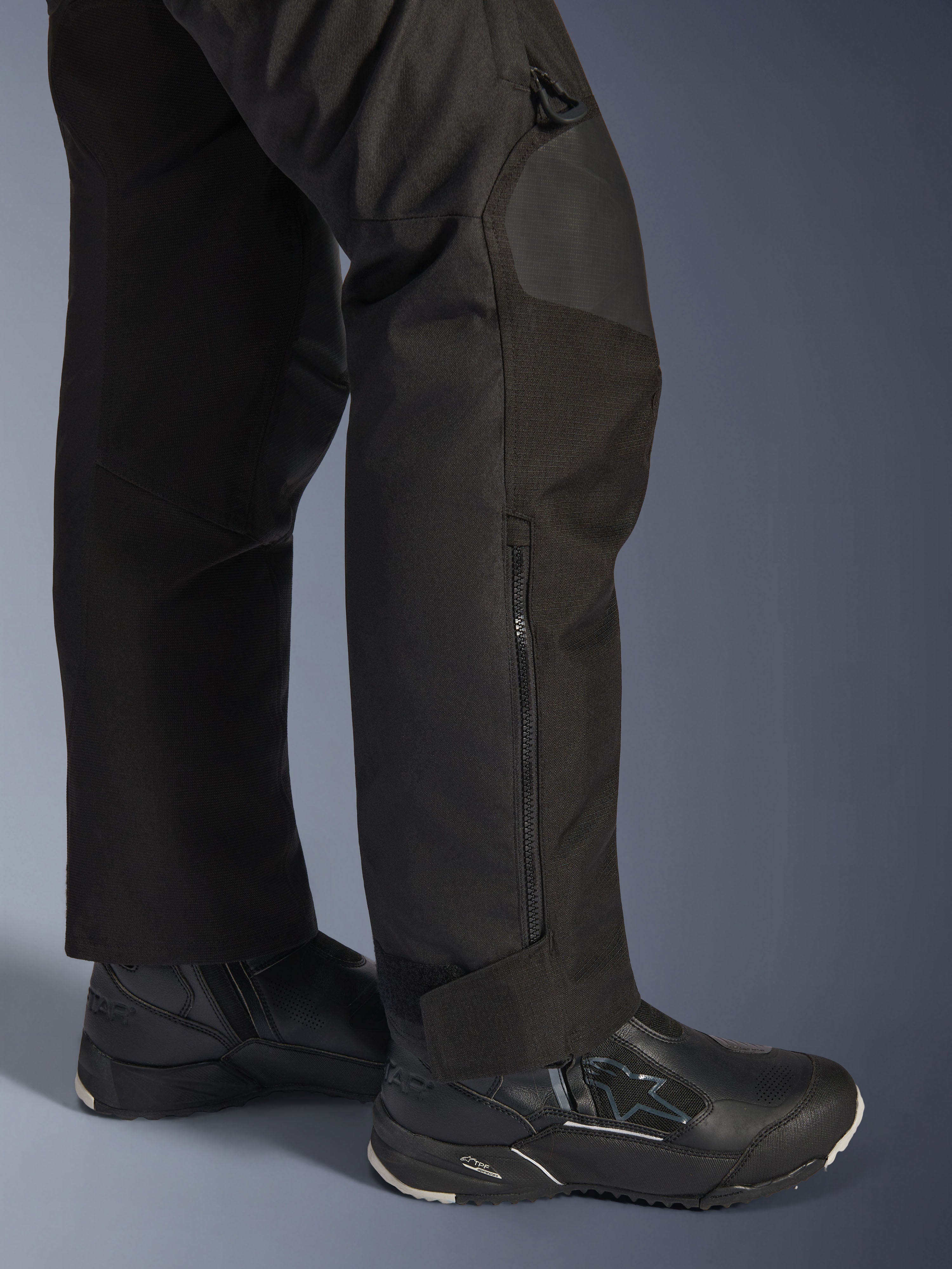 Alpinestars Stella Andes V4 Drystar® Pants, pantaloni da moto da donna, nero, dettaglio della parte inferiore della gamba con zip laterale e chiusura regolabile alla caviglia, indossati con stivali da moto Alpinestars neri