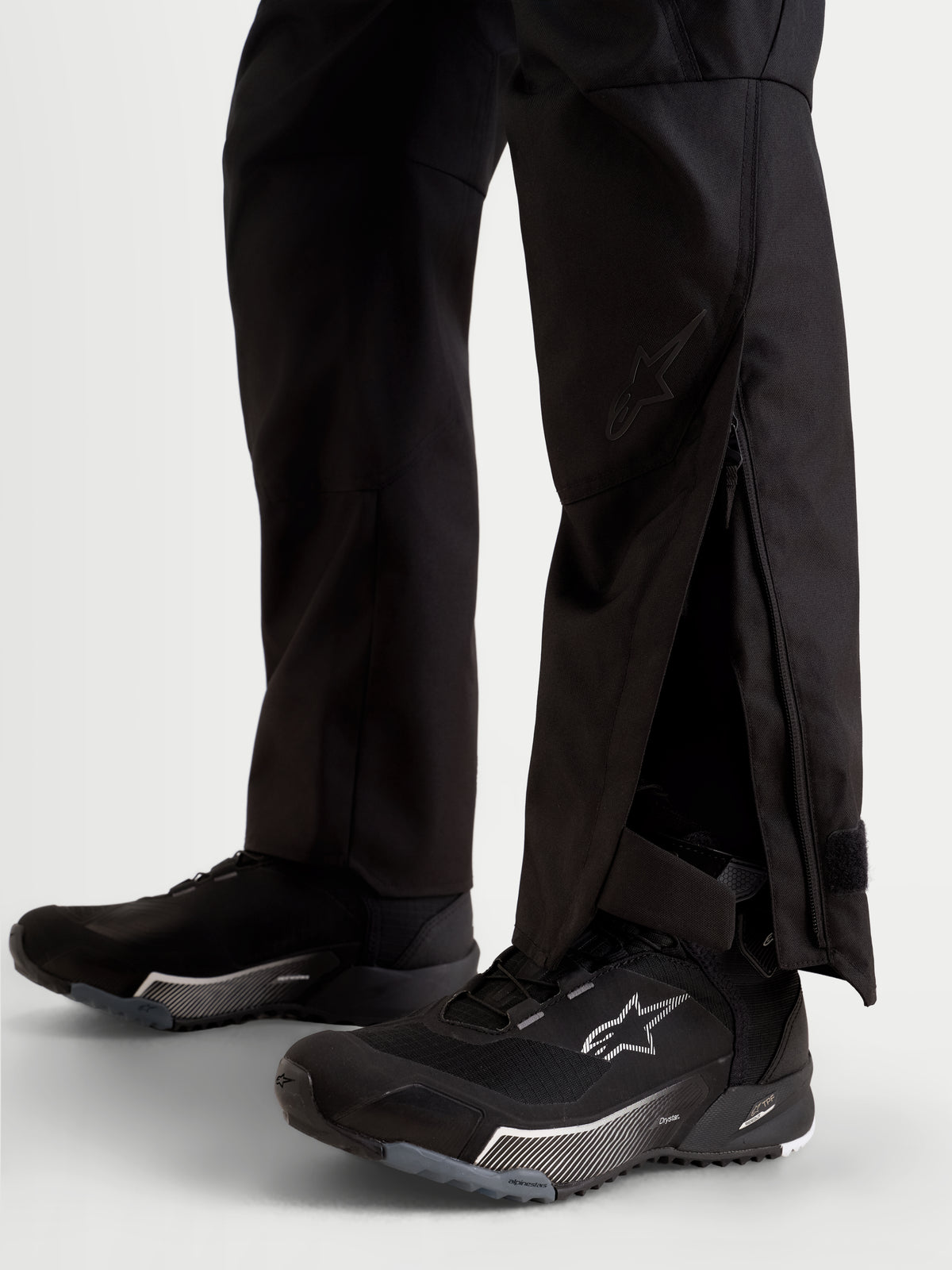 Alpinestars Stella C-1 Waterproof Pantaloni, pantaloni da moto urbani contemporanei da donna, colore nero, vista in primo piano con aperture estese sulla parte inferiore della gamba dotate di soffietti con cerniera indossati sopra le scarpe da moto