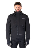 Alpinestars Mootant Waterproof Parka, giacca da moto nera con cappuccio dal design tecnico modulare, indossata da un modello con guanti neri, caratterizzata da un'esclusiva patta sul petto e tasche laterali con zip, stile urban e touring.