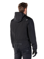Alpinestars Mootant Waterproof Parka, giacca da moto nera, vista posteriore con design con cappuccio, logo bianco sulla spalla e marchio riflettente MO.ST.EQ. sulla parte bassa della schiena, abbigliamento tecnico urban contemporary