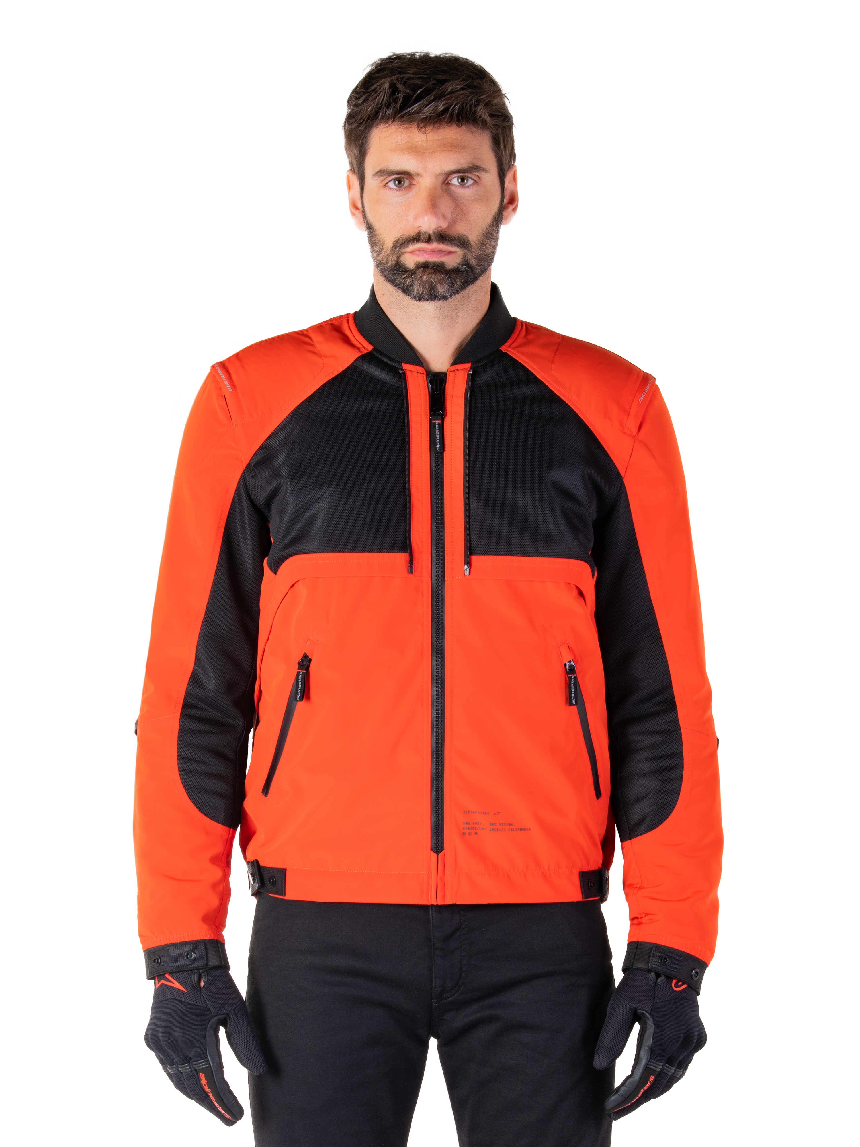 Alpinestars Mootant Waterproof Parka in Spicy Orange e nero, giacca da moto modulare mostrata in configurazione stile bomber su un modello maschile, con pannelli in rete nera sulla parte superiore del torace, busto e maniche arancione acceso, cerniera frontale e colletto a costine, abbinata a guanti e pantaloni neri
