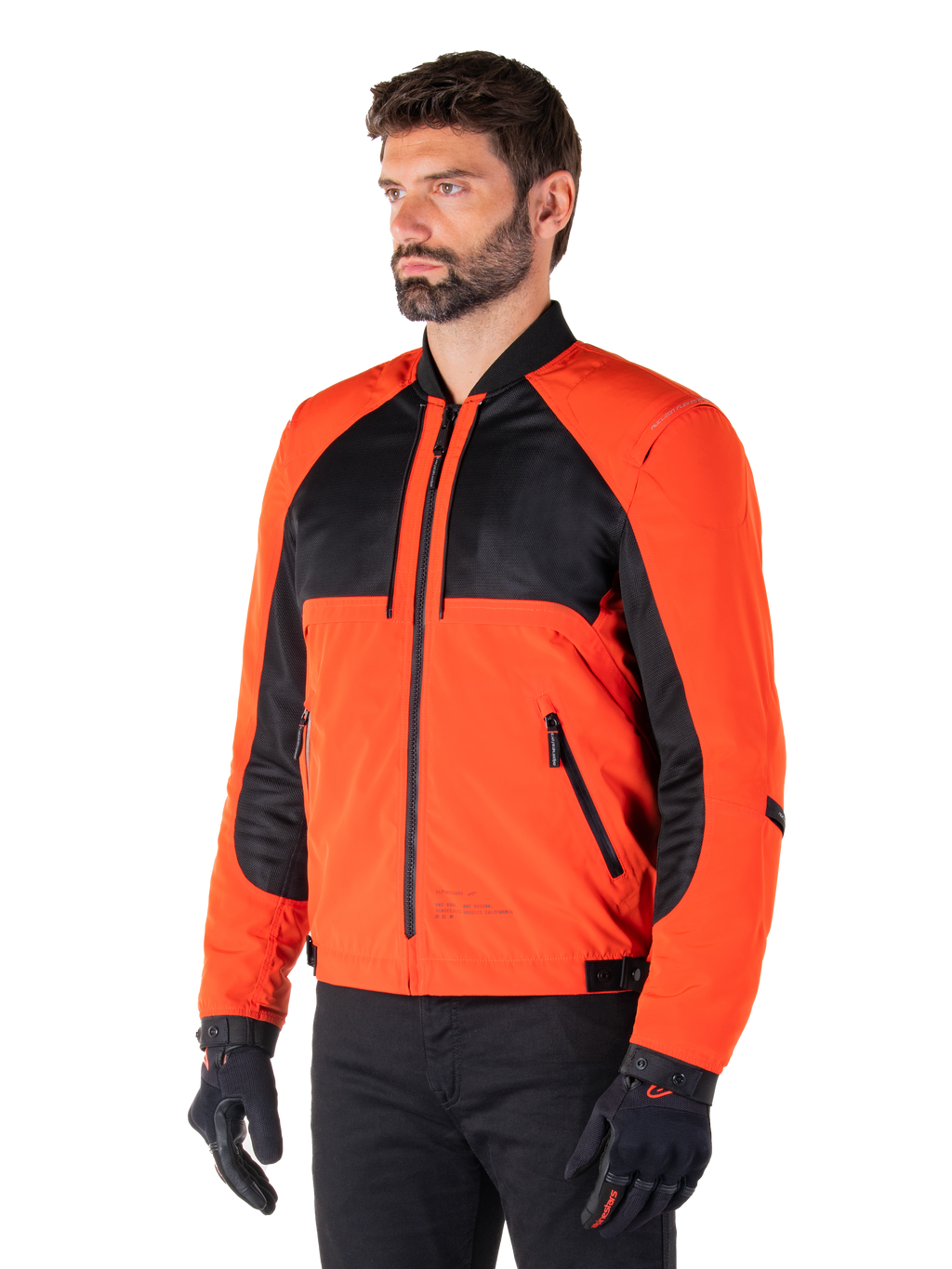 Alpinestars Mootant Waterproof Parka in Spicy Orange e nero, giacca da moto modulare mostrata nella sua configurazione bomber, presenta pannelli in mesh nero e tessuto arancione, abbigliamento tecnico urbano contemporaneo indossato con guanti neri