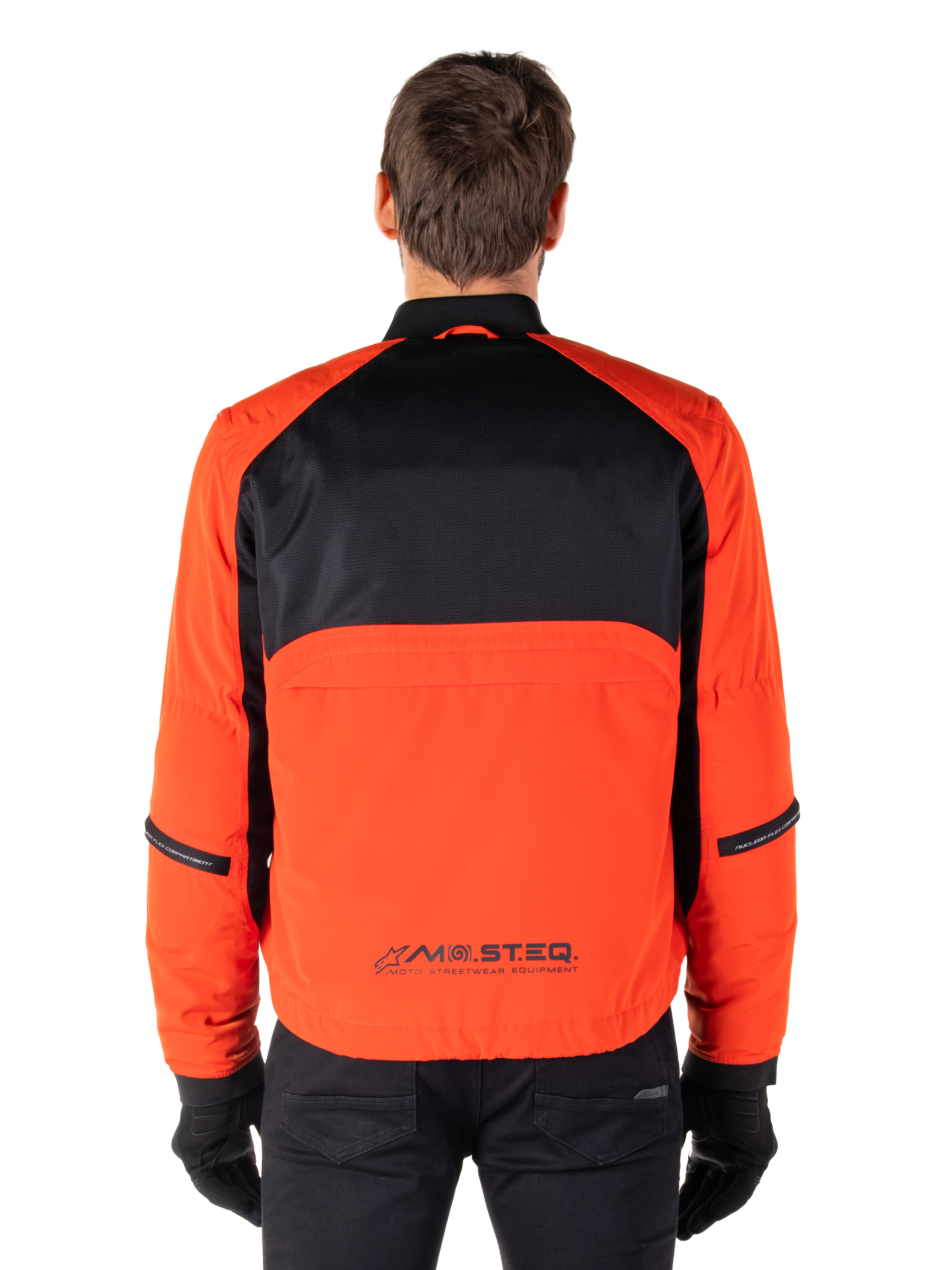 Alpinestars Parka impermeabile Mootant, giacca da moto, arancione e nero, vista posteriore, con parte superiore della schiena in mesh nero e pannello inferiore arancione con logo MO.ST.EQ., indossato con pantaloni e guanti neri
