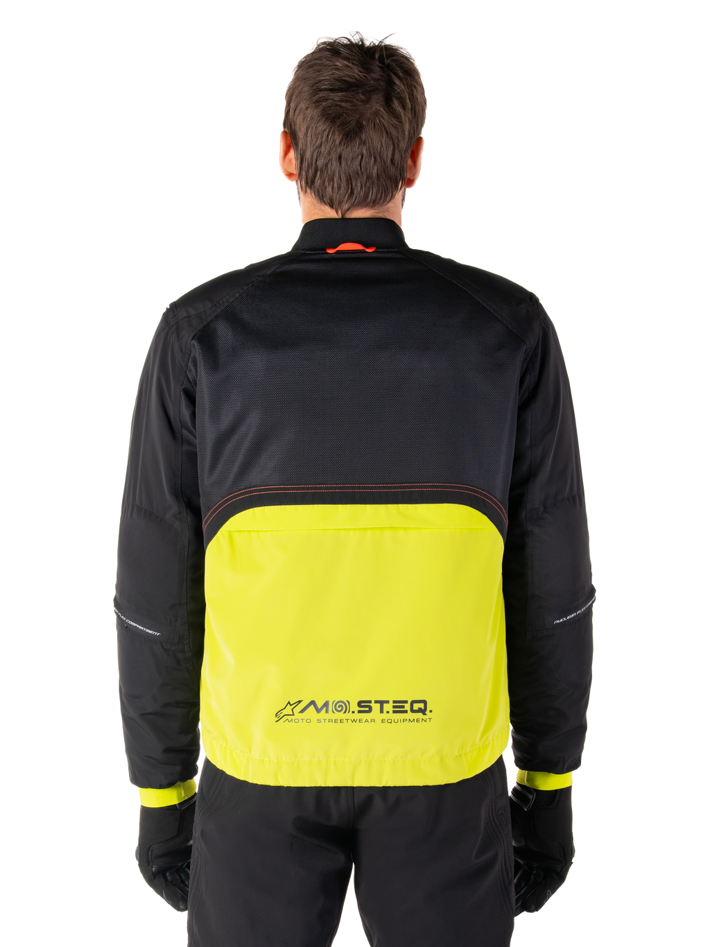 Alpinestars Mootant Waterproof Parka, giacca da moto, Lime Punch e nero, vista posteriore con parte superiore in rete nera per la ventilazione e sezione inferiore lime con logo MO.ST.EQ., indossata con pantaloni e guanti neri