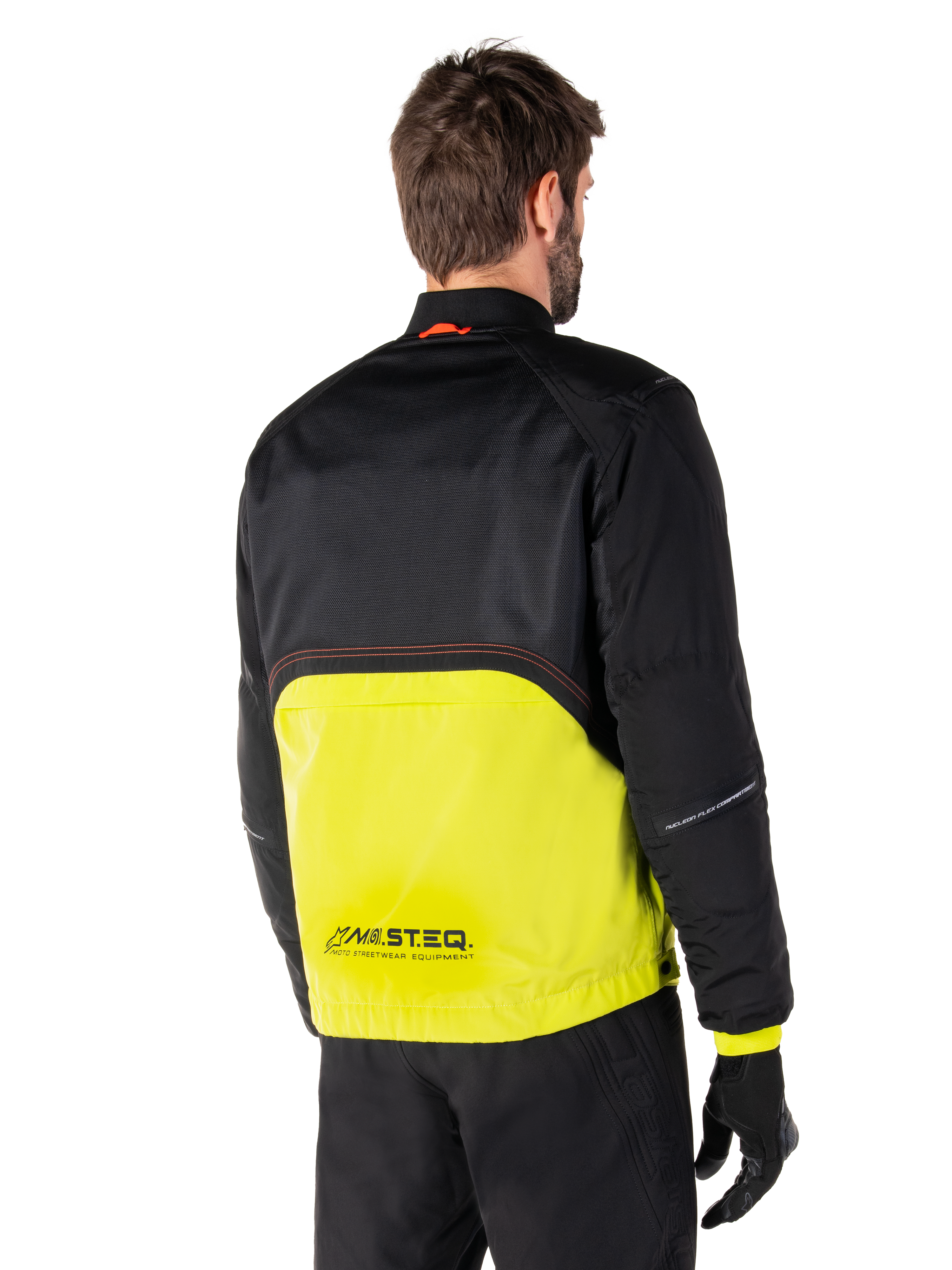 Alpinestars Mootant Waterproof Parka, giacca da moto, Lime Punch e nero, vista posteriore con parte superiore in rete nera e sezione inferiore verde lime brillante, marchio MO.ST.EQ., indossata con pantaloni e guanti da moto neri