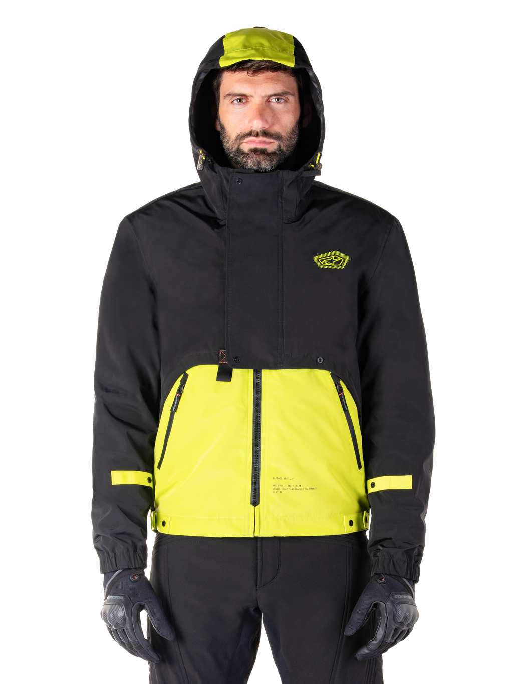Alpinestars Mootant Waterproof Parka, giacca da moto Lime Punch Black, vista frontale, design modulare 3-in-1 con parte superiore nera e sezione inferiore verde lime brillante, dotata di cappuccio con coulisse e logo sul petto, indossata con pantaloni neri e guanti da moto