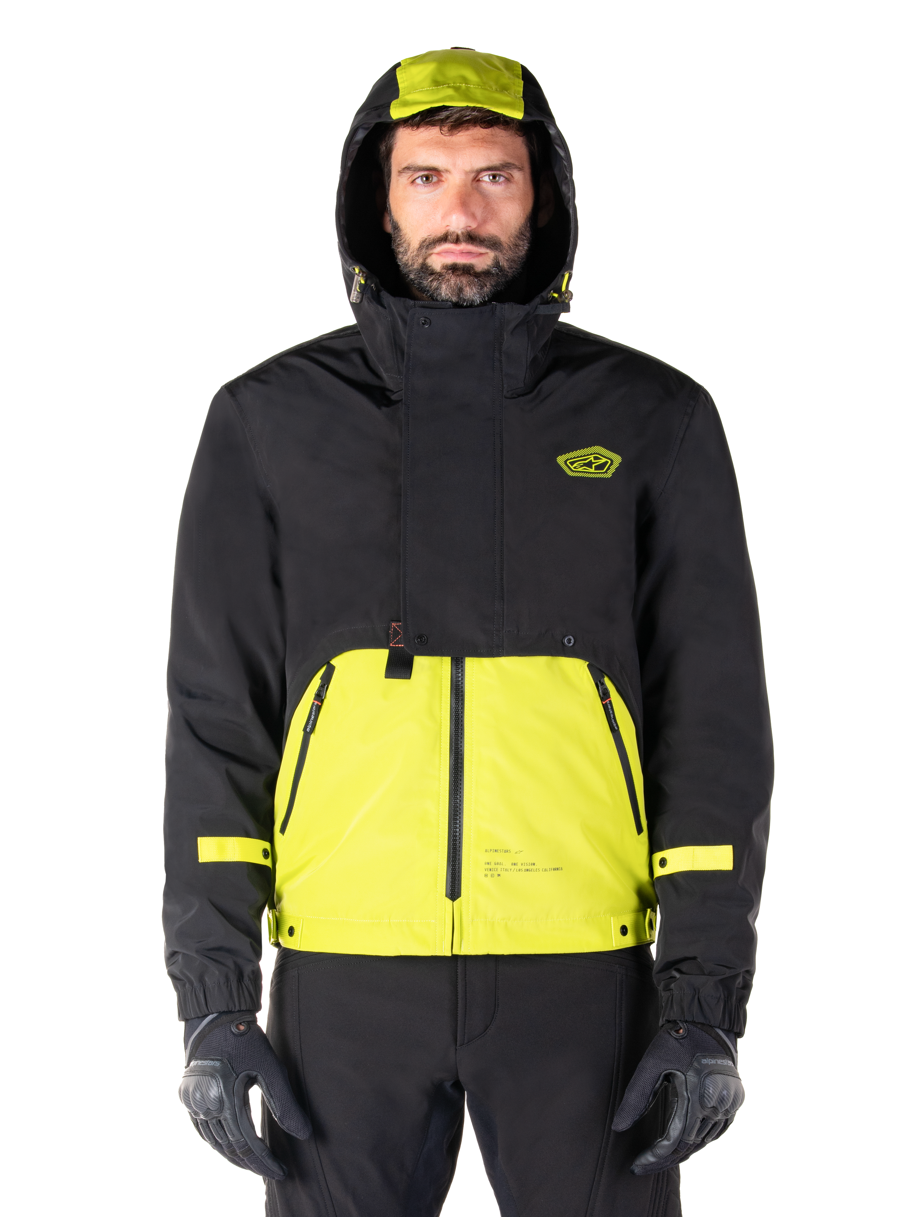 Alpinestars Mootant Waterproof Parka, giacca da moto Lime Punch Black, vista frontale, design modulare 3-in-1 con parte superiore nera e sezione inferiore verde lime brillante, dotata di cappuccio con coulisse e logo sul petto, indossata con pantaloni neri e guanti da moto