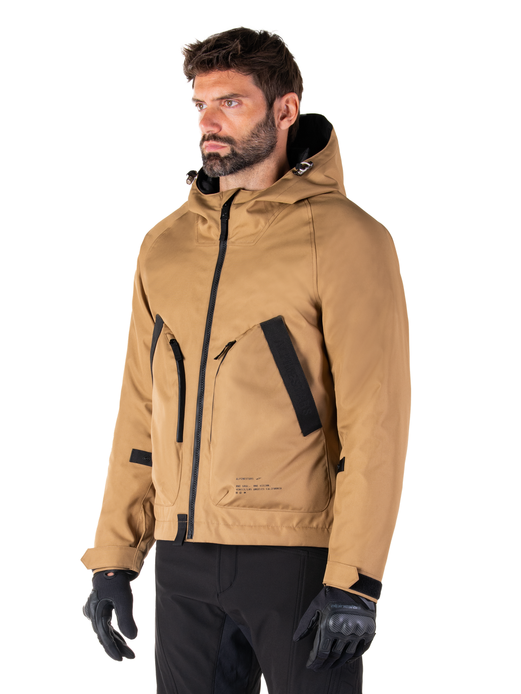 Alpinestars Morush Parka impermeabile, marrone (Utility Brown), modello maschile che indossa il parka con guanti da moto neri e pantaloni neri, design minimalista d'ispirazione streetwear con cappuccio a prova di maltempo e ampie tasche frontali, abbigliamento da moto impermeabile