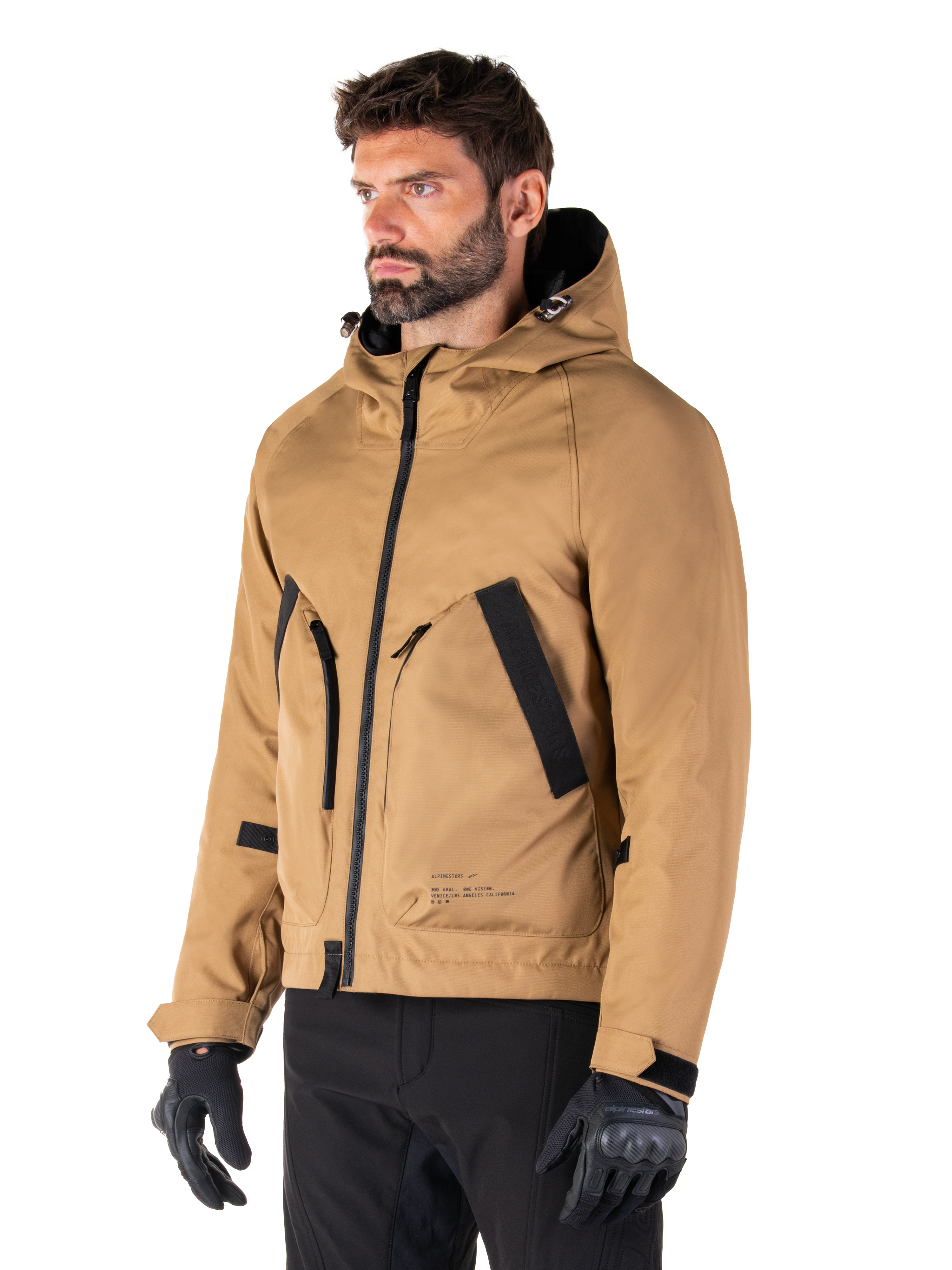 Alpinestars Morush Parka impermeabile, marrone (Utility Brown), modello maschile che indossa il parka con guanti da moto neri e pantaloni neri, design minimalista d'ispirazione streetwear con cappuccio a prova di maltempo e ampie tasche frontali, abbigliamento da moto impermeabile