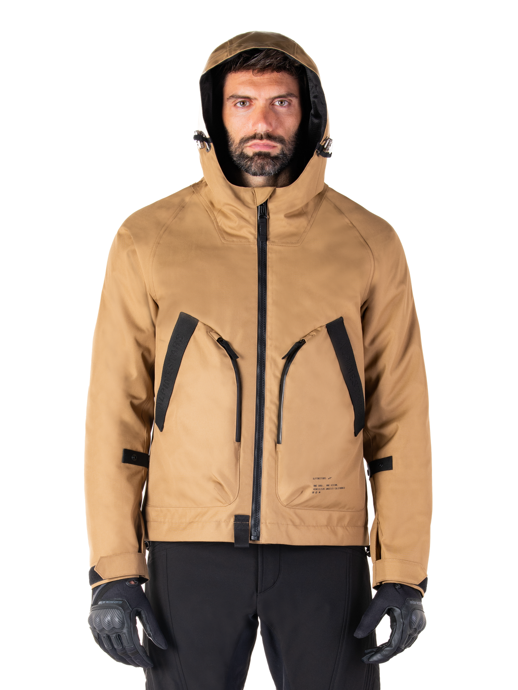 Alpinestars Morush Waterproof Parka, giacca da moto, marrone utility, design con cappuccio ispirato allo streetwear con ampie tasche anteriori con accenti neri, indossata con guanti da moto e pantaloni neri, abbigliamento moto urban contemporary