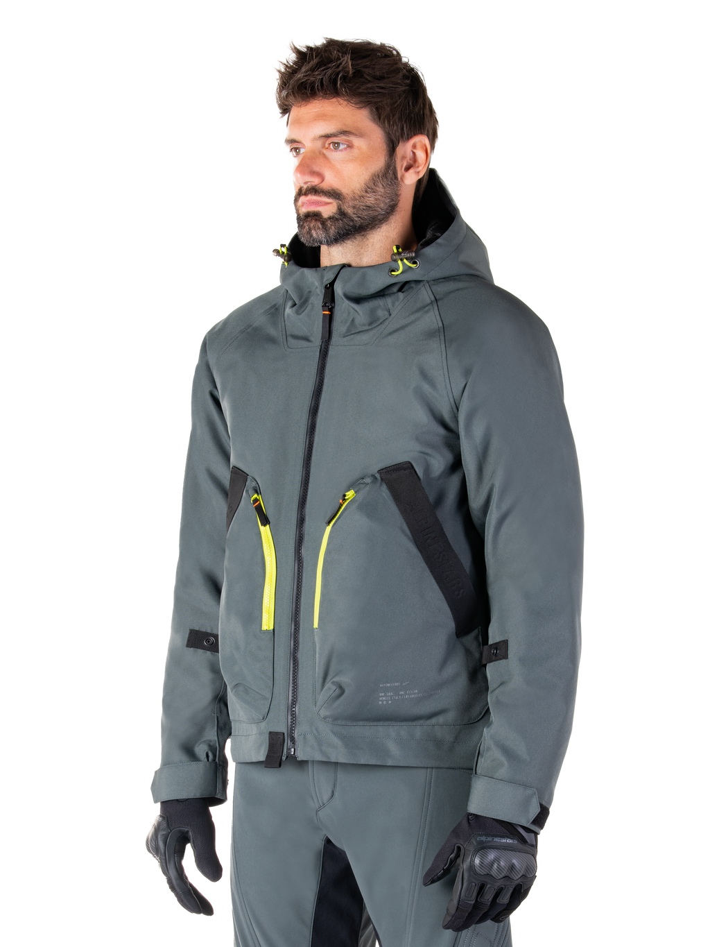 Alpinestars Morush Waterproof Parka, giacca da moto Urban Gray, design con cappuccio e dettagli delle zip in giallo acceso, rifiniture delle tasche nere, indossato con pantaloni da moto grigi coordinati e guanti neri, abbigliamento da moto contemporaneo ispirato allo streetwear.