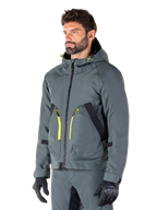 Alpinestars Morush Waterproof Parka, giacca da moto Urban Gray, design con cappuccio e dettagli delle zip in giallo acceso, rifiniture delle tasche nere, indossato con pantaloni da moto grigi coordinati e guanti neri, abbigliamento da moto contemporaneo ispirato allo streetwear.