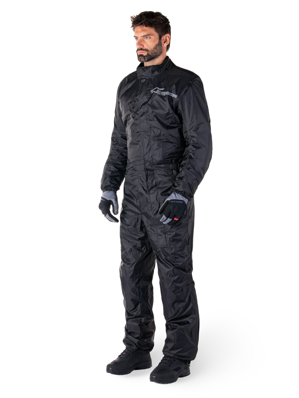 Tuta Alpinestars Hurricane Rain V2, nero, tuta antipioggia integrale da moto impermeabile, indossata con guanti e stivali, con logo Alpinestars riflettente sul petto, design leggero per la protezione in caso di pioggia