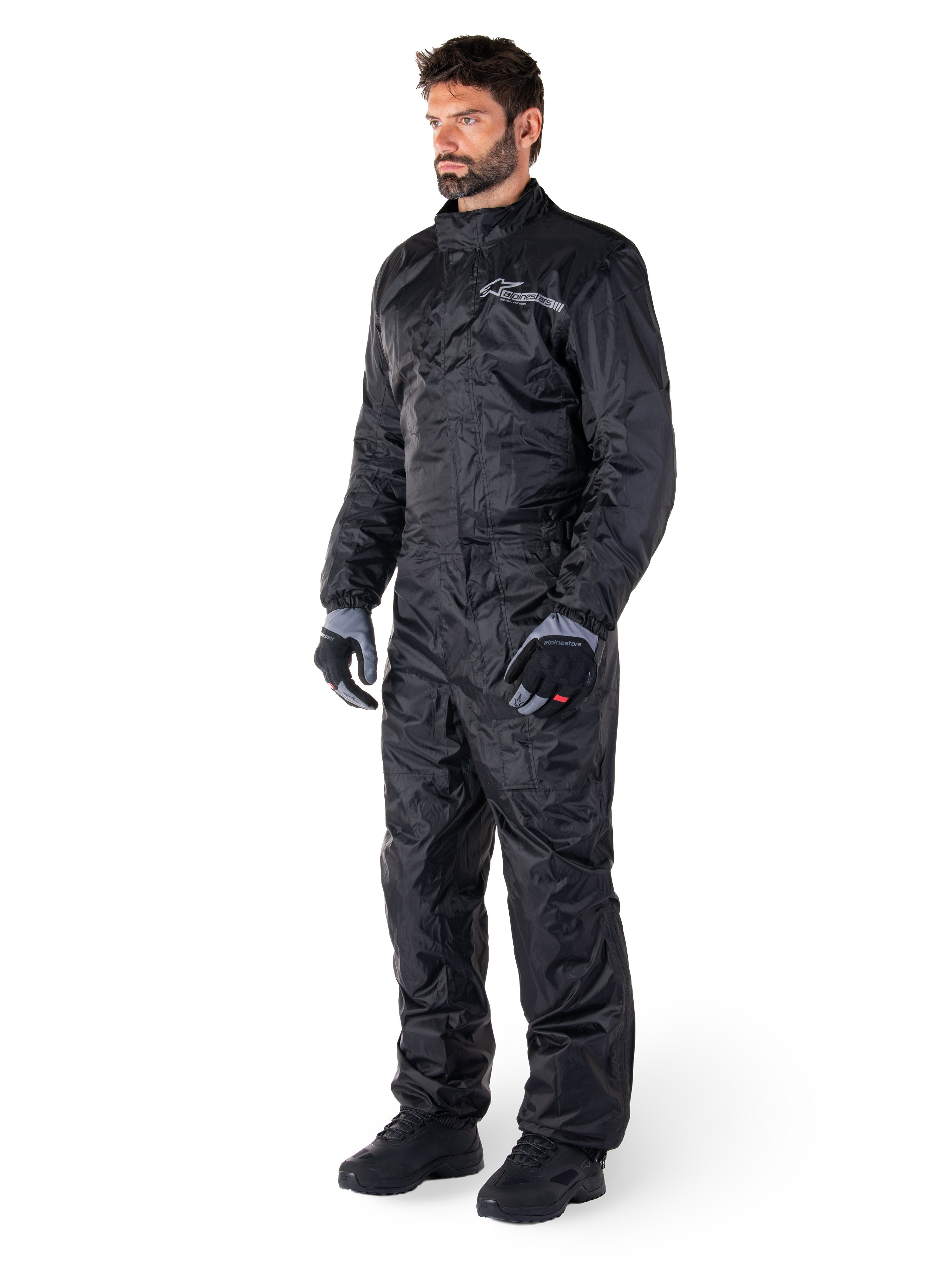Tuta Alpinestars Hurricane Rain V2, nero, tuta antipioggia integrale da moto impermeabile, indossata con guanti e stivali, con logo Alpinestars riflettente sul petto, design leggero per la protezione in caso di pioggia