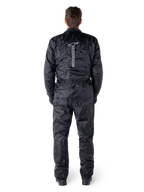 Tuta Alpinestars Hurricane Rain V2, tuta da moto intera impermeabile nera, vista posteriore che mostra il grande logo e la scritta Alpinestars in verticale, tessuto leggero stropicciato con vita e polsini elasticizzati, progettata per la protezione durante la guida in condizioni di bagnato.